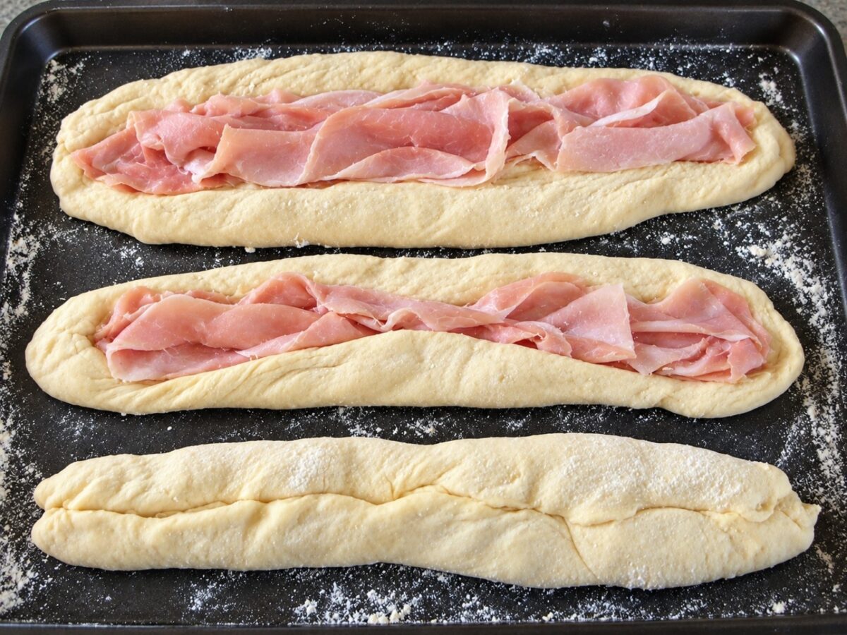 Baguette di pasta cruda farcite con fette di prosciutto cotto prima di essere chiuse