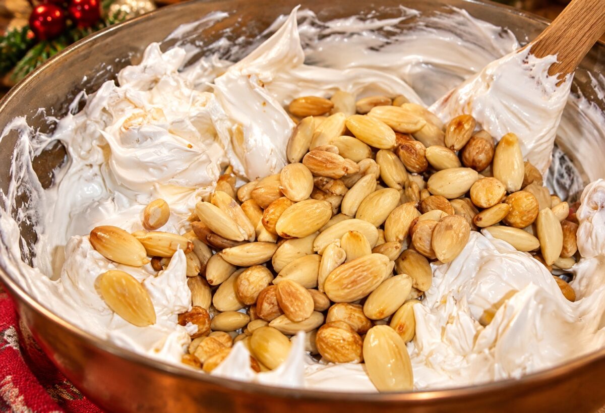 Mandorle intere unite al composto bianco del torrone durante la preparazione